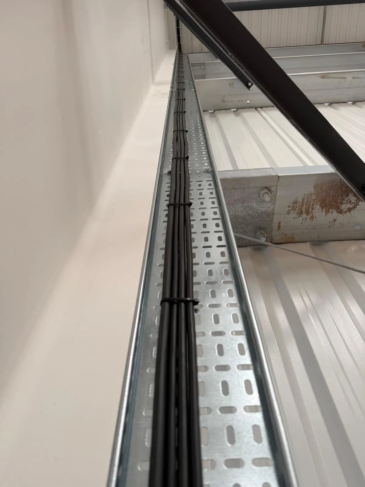 Cable tray installation running along warehouse ceiling â€” commercial electrician Cheshire