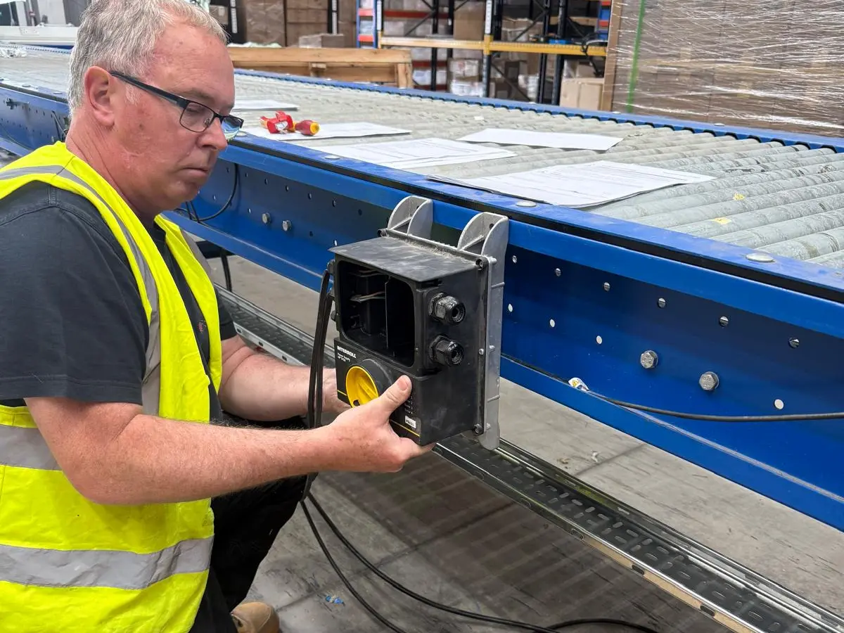 Electrician fitting a Interroll conveyor drive control unit during a warehouse conveyor power installation by Portcullis Power Solutions